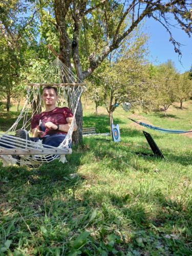a man sitting in a hammock in a park at Djedova koliba in Žabljak