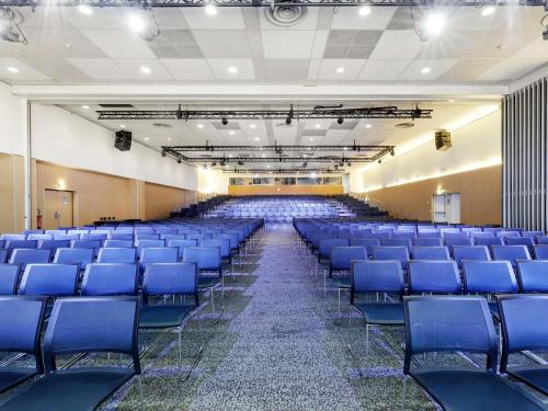 an empty auditorium with blue chairs in a hall at Novotel Paris Est Centre de Conférence in Bagnolet