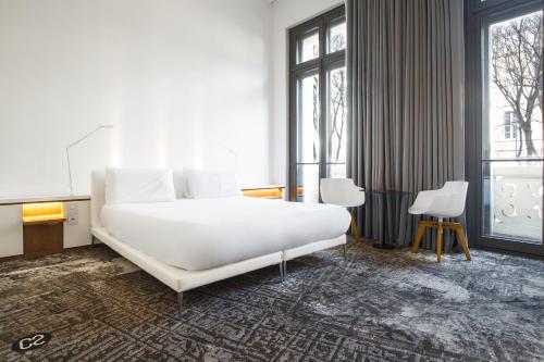 a bedroom with a large white bed and windows at Hôtel C2 in Marseille