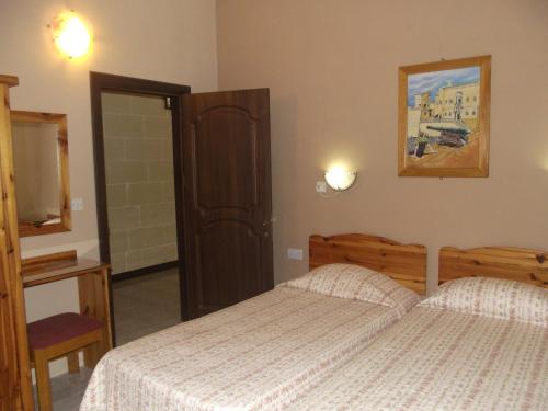 a bedroom with two beds and a door to a bathroom at Sunset Seaview Accommodation in Marsalforn