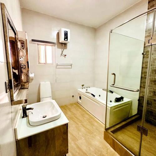 a bathroom with a tub and a sink and a shower at Julaz Apartment in Lagos