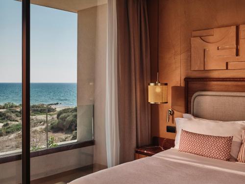 a bedroom with a bed and a view of the ocean at Icona's Costa Ragusa Resort - New Opening in Scoglitti