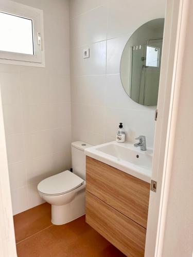 a bathroom with a toilet and a sink and a mirror at Villa Gabriela in S'Algar