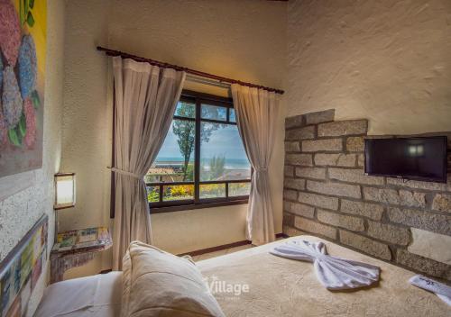 a bedroom with a bed and a large window at Village Praia do Rosa in Praia do Rosa