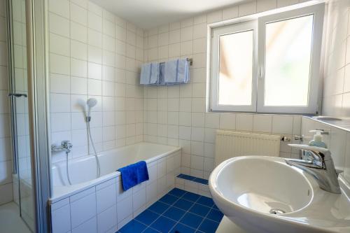 a white bathroom with a tub and a sink at Ferienwohnung Ledergerber in Bodman-Ludwigshafen