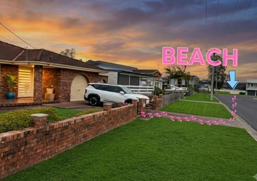a house with a lawn in front of a house with the words beach at 100m to Beach&Shop Spacious Pristine One Story Family Home in Batemans Bay