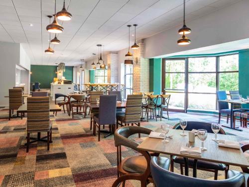 a restaurant with tables and chairs and windows at Novotel Newcastle Airport in Newcastle upon Tyne