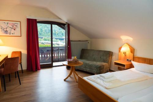 a bedroom with a bed and a couch and a table at Alembra - Hotel zur Moselbrücke in Schweich