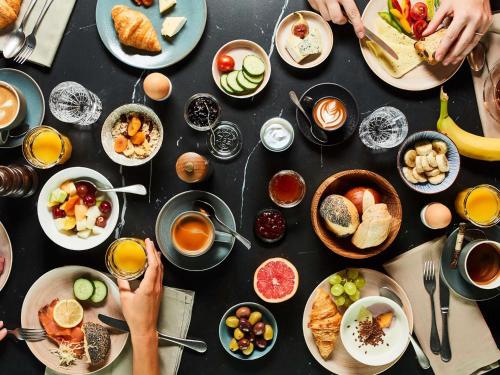 a table with plates of breakfast foods and drinks at Hotel Am Konzerthaus - MGallery Collection in Vienna