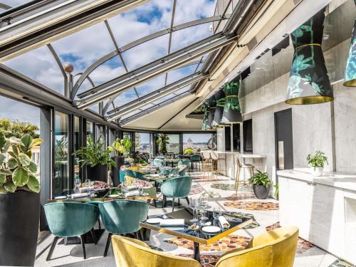 ein Restaurant mit Stühlen, Tischen und Fenstern in der Unterkunft Sofitel Roma Villa Borghese in Rom