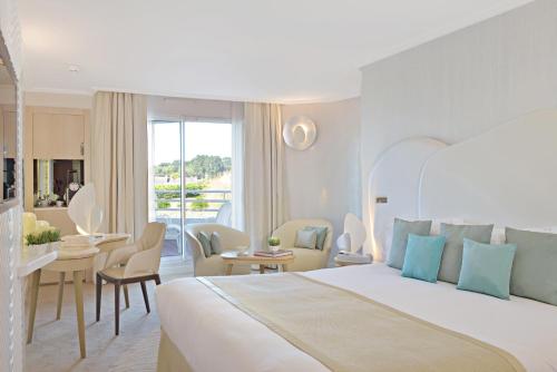 a bedroom with a large bed and a living room at Miramar La Cigale Hotel Thalasso & Spa in Arzon