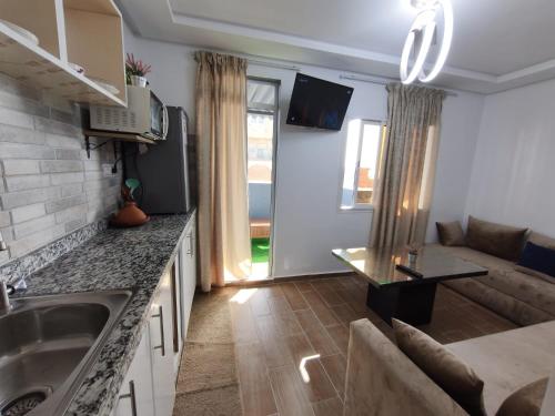 a kitchen with a sink and a living room at Younes résidence 2 in Asilah