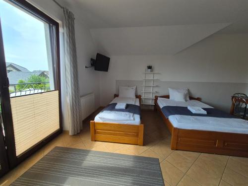 two beds in a room with a large window at Malinowe Lato in Grzybowo
