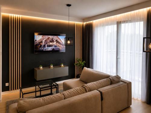 a living room with a couch and a tv on a wall at Apartamenty Royal in Bartoszyce