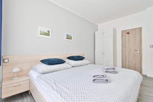 a white bedroom with a large bed with blue pillows at Apartmán na výsluní in Luhačovice