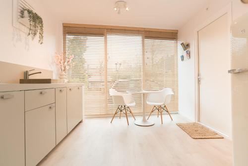 a kitchen with a table and two white chairs at Studio Loet in Schagen