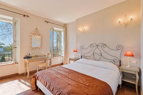 a bedroom with a bed and a desk and windows at Hostellerie du Cigalou in Bormes-les-Mimosas