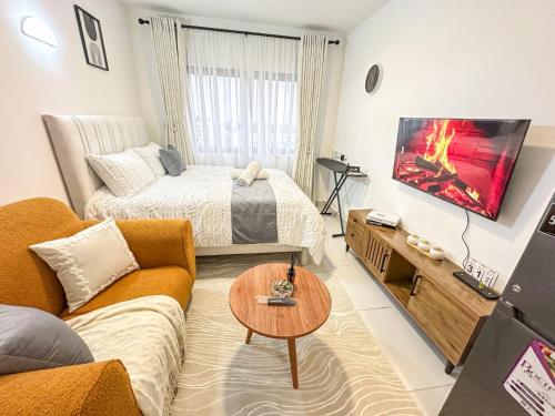 a living room with a couch and a bed and a tv at Luxore apartment in Syokimau