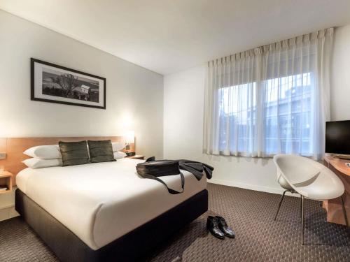 a hotel room with a bed and a desk and a television at ibis Melbourne Hotel and Apartments in Melbourne