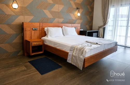 a bedroom with a large bed with a wooden headboard at Résidence Houé in Lomé