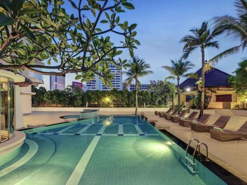 a swimming pool with chaise lounges and a resort at Mercure Jakarta Kota in Jakarta