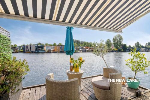 a patio with a table and chairs next to the water at The New Lake Boathouse in Amsterdam