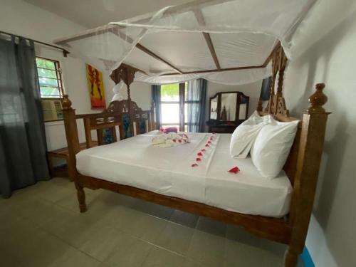 a bedroom with a canopy bed with red cards on it at Zuri Sana Beach Hotel in Kepwani