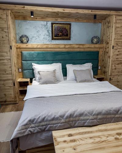 a bedroom with a large bed with a blue headboard at La Colțul Castelului Bran Boutique in Bran