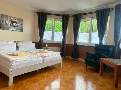 a bedroom with a bed and a chair and windows at Hotel garni SEESCHLÖSSCHEN in Kölpinsee