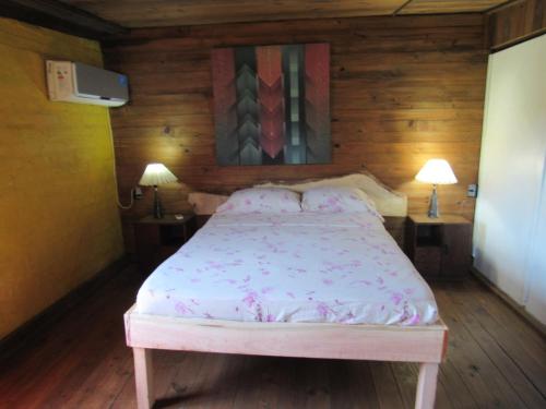 a bed in a room with two tables and two lamps at Casa de huéspedes cochera cubierta in Oberá