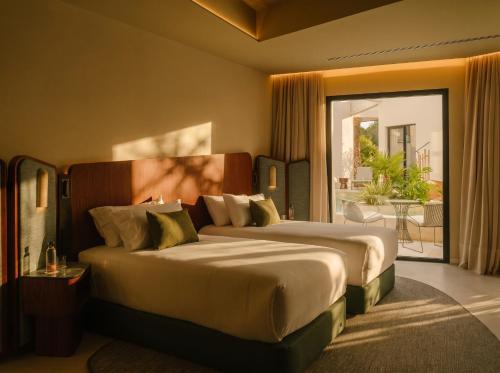 a hotel room with two beds and a balcony at RIVELIAN Grand Menorca in Menorca