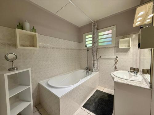 a white bathroom with a tub and a sink at Bungalow Tec-Tec Proche plage et centre Saint Leu in Saint-Leu