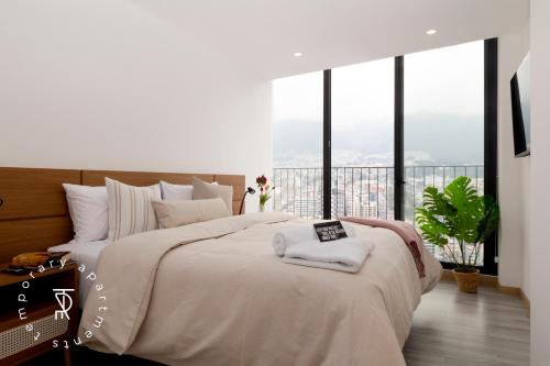 a bedroom with a large bed with a large window at Top Rentals EpiQ in Quito