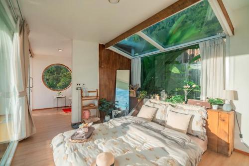 a bedroom with a bed and a large window at Phupetra in Ban Thung Phan Ha
