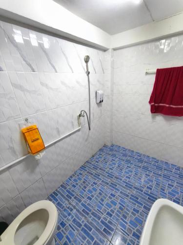 a bathroom with a toilet and a blue tile floor at taitoon hostel&cafe in Chiang Rai