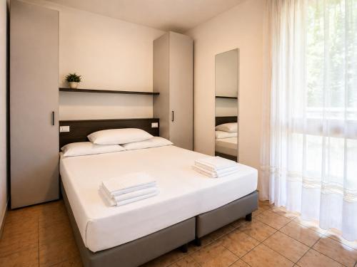 a bedroom with a large white bed and a window at Residence Columbia in Bibione
