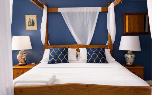 a bedroom with a bed with blue walls and two lamps at Le Gîte des Violettes in Ger