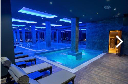 a large swimming pool in a building with blue lighting at Apartmani Pužić in Kopaonik
