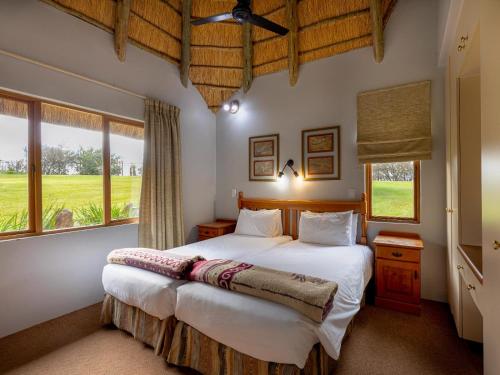a bedroom with a large bed and two windows at Montusi Self-Catering Cottages in Bergville