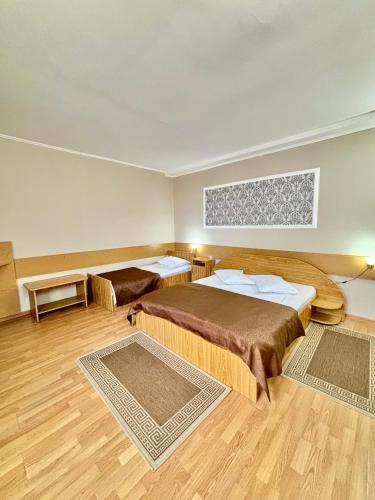 a hotel room with two beds and wooden floors at Hotel Perla in Satu Mare