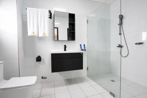 a white bathroom with a sink and a shower at Cinq Cent Vingt Hotel & Residence in Abidjan