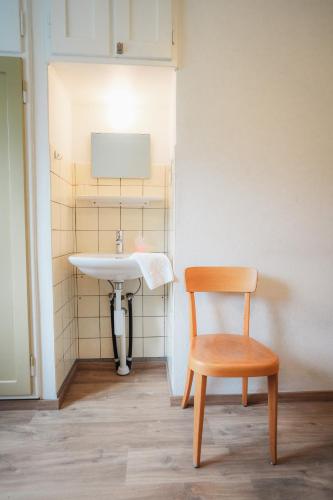 a bathroom with a wooden chair and a sink at Hotel Haus Schönstatt contactless-Check-In in Brig