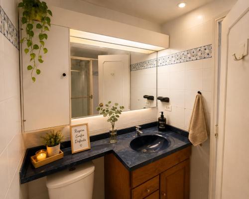 a bathroom with a sink and a mirror and a toilet at Hostel Casa Unicentro in Bogotá