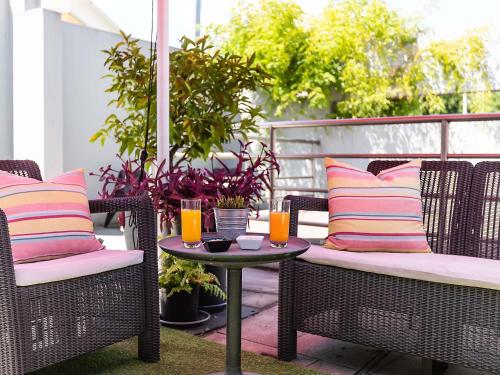 a patio with two chairs and a table with drinks on it at Hotel ibis Guimaraes in Guimarães