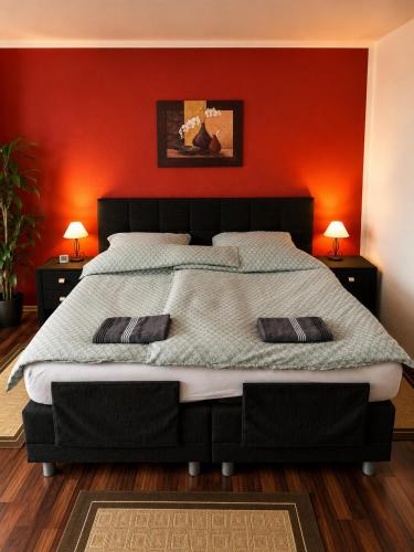 a bedroom with a large bed with a red wall at Pension Zum Rödereck in Zeithain