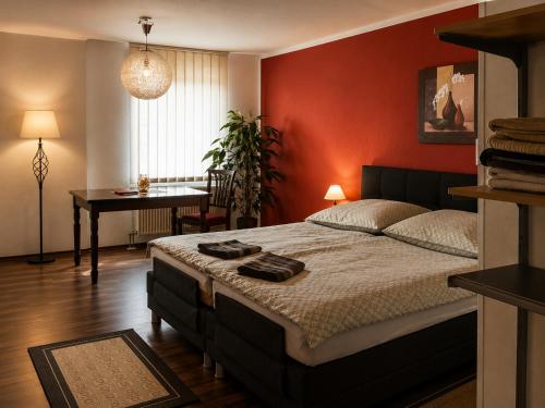 a bedroom with a bed with a red wall at Pension Zum Rödereck in Zeithain