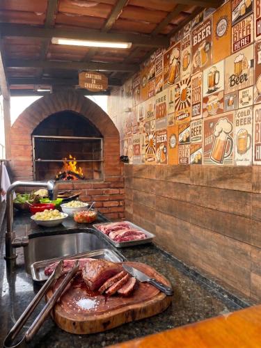 a kitchen with a counter with meat and a fireplace at Apartamento 3 Quartos, Churrasqueira, Vista Mar, Varanda, 5 min da praia in Guarapari