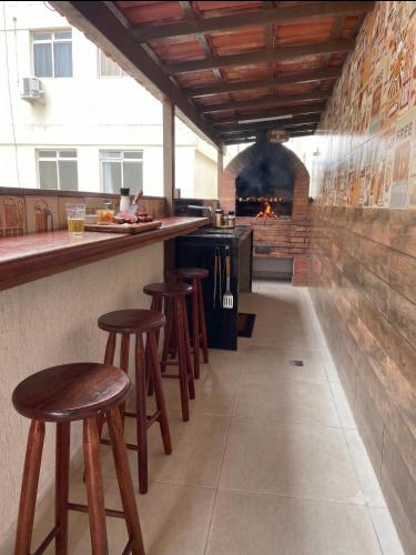 a bar with stools in a kitchen with a fireplace at Apartamento 3 Quartos, Churrasqueira, Vista Mar, Varanda, 5 min da praia in Guarapari