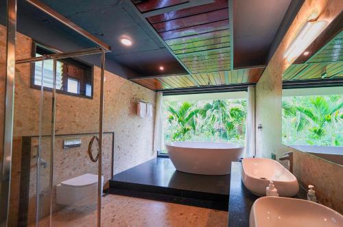 a bathroom with a tub and two sinks and a shower at Open Hotel by Olive - Biranji Aqua Reatreat in Chikmagalūr