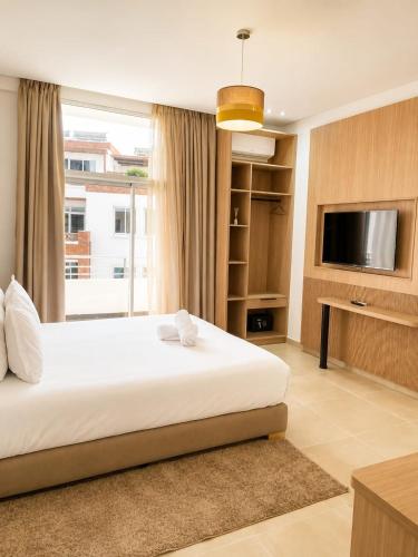 a bedroom with a bed and a flat screen tv at Sables D'or Appart Hôtel in Agadir